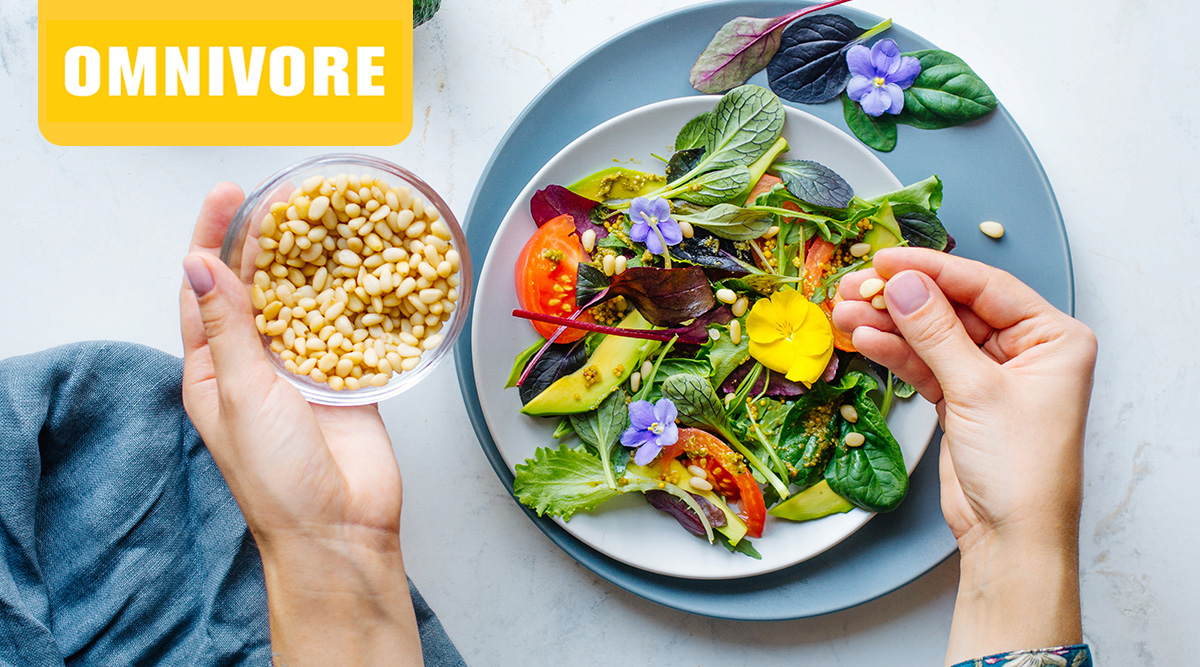 Omnivore logo. Hands adding pine nuts to a colorful salad.